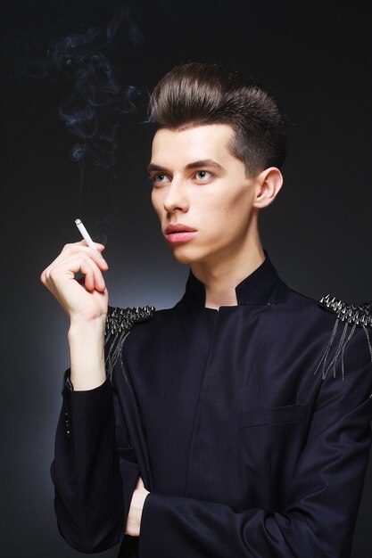 Young stylish man smoking a cigarette. Studio shot.