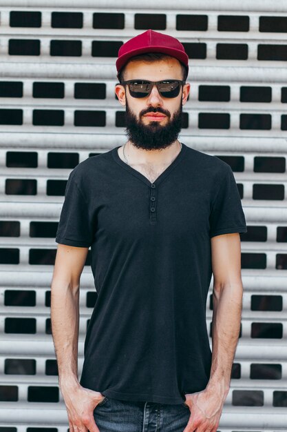 Un giovane uomo alla moda con la barba in una maglietta nera e occhiali