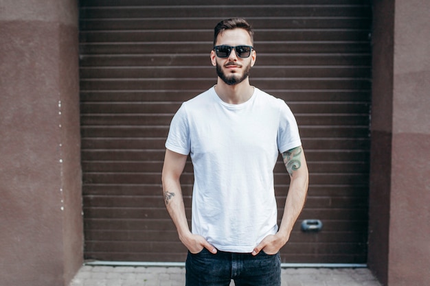 Photo a young stylish man with a beard in a white t-shirt and glasses