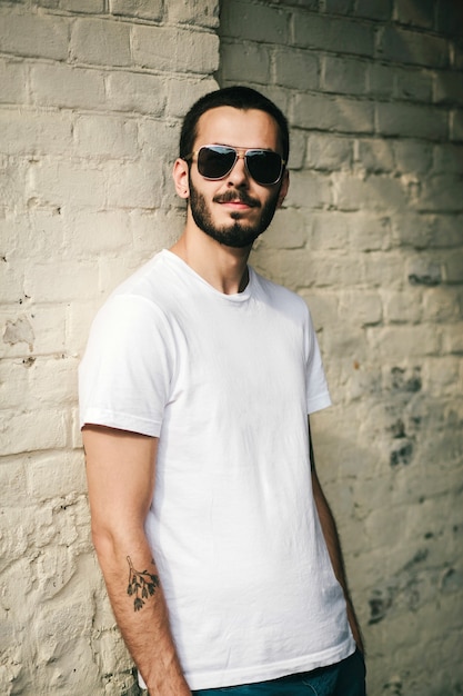 Young stylish man with beard in white T-shirt and glasses