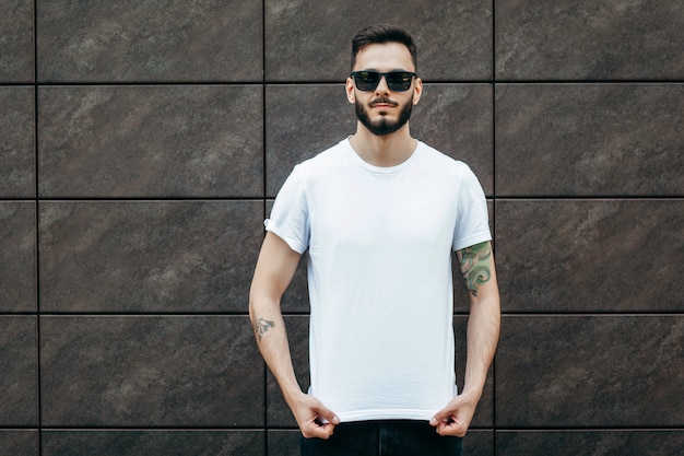 A young stylish man with a beard in a white t-shirt and sunglasses