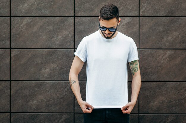 A young stylish man with a beard in a white t-shirt and sunglasses