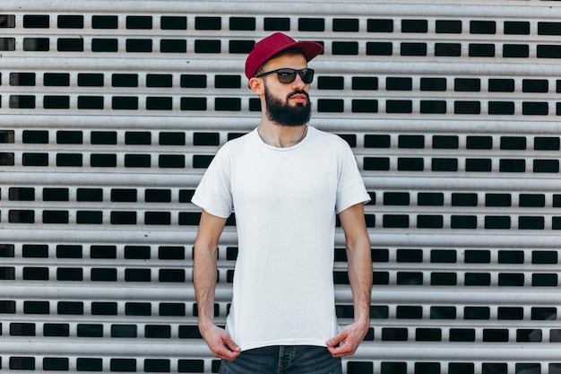 A young stylish man with a beard in a white Tshirt and glasses