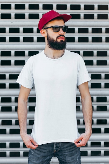 A young stylish man with a beard in a white Tshirt and glasses