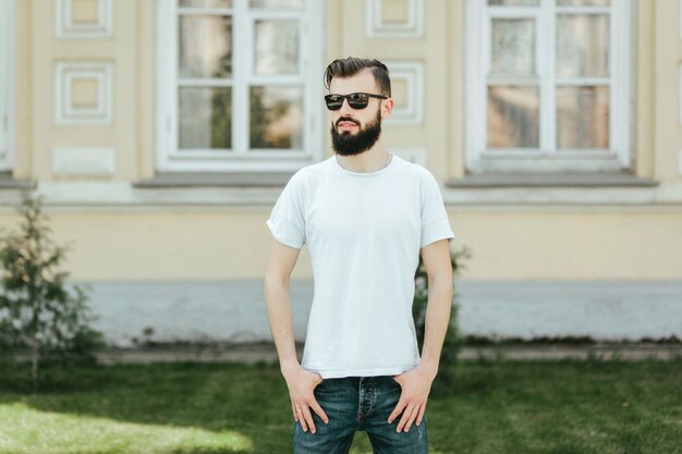 A young stylish man with a beard in a white Tshirt and glasses