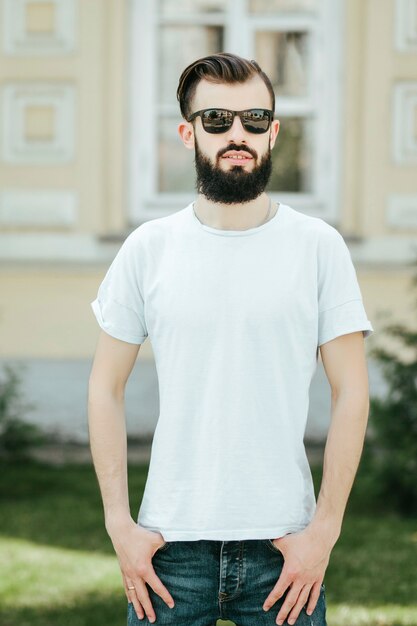 A young stylish man with a beard in a white Tshirt and glasses