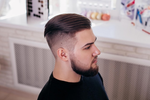 Young stylish man with fashion haircut on barbershop background