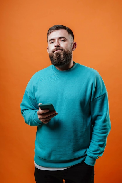 Young stylish man with a phone in his hands on an orange background