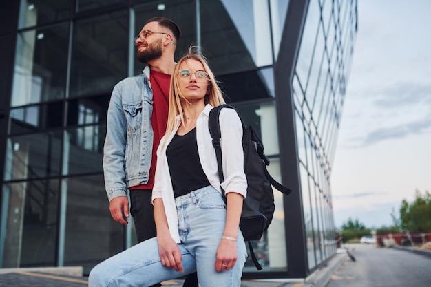 Young stylish man with woman in casual clothes outdoors together near business building Conception of friendship or relationships