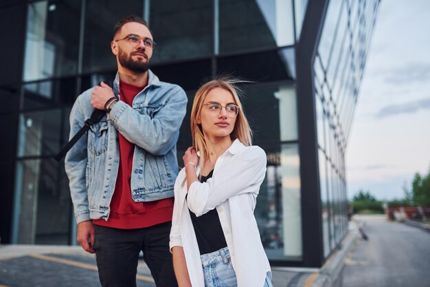 Giovane uomo alla moda con donna in abiti casual all'aperto insieme vicino alla costruzione di affari concezione di amicizia o relazioni