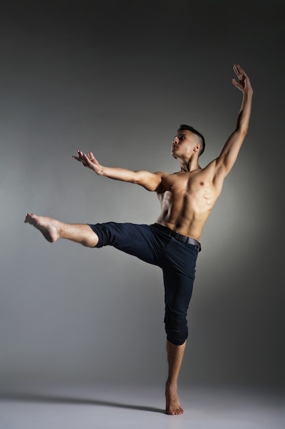 Young and stylish modern ballet dancer on grey background