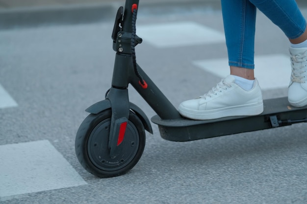 A young stylish Muslim woman in a fashion hijab rides an electric scooter in the city