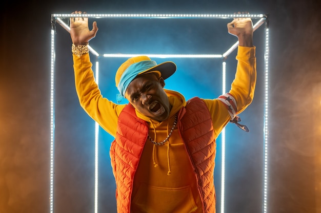 Il giovane rapper alla moda posa nel cubo illuminato. interprete hip-hop, cantante rap, performance di breakdance, stile di vita di intrattenimento