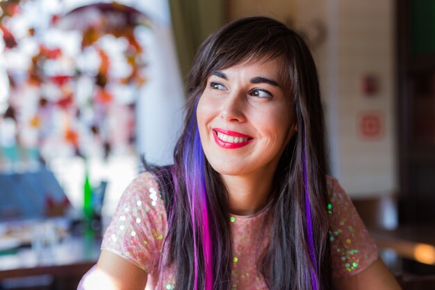 Молодая стильная модная женщина с разноцветной прядью в волосах сидит в кафе