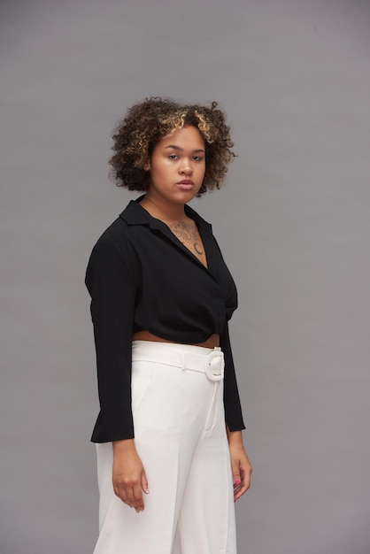 Young stylish woman in black blouse with long sleeves and white pants