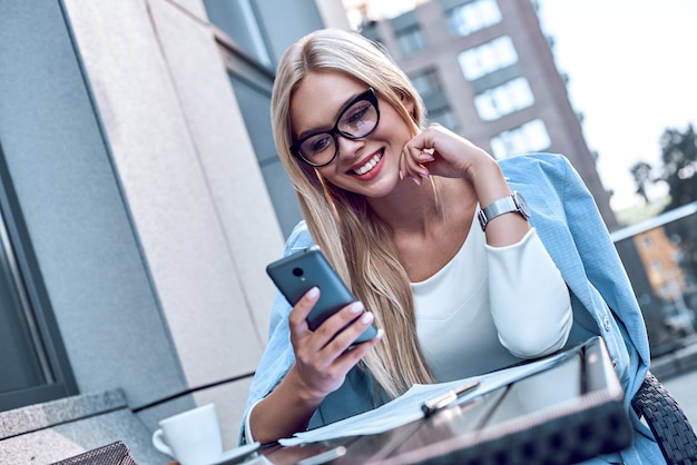 カフェでスマートフォンでおしゃべり若いスタイリッシュな女性