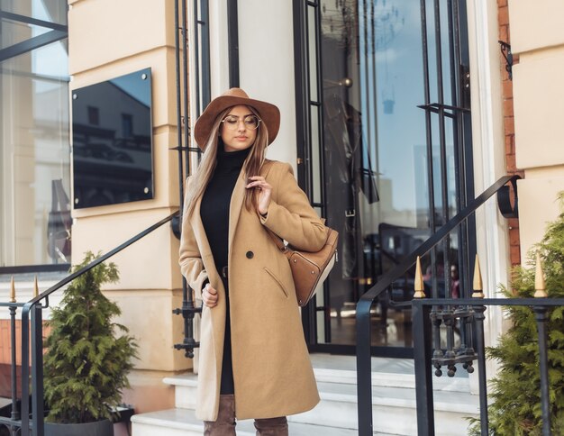 Giovane donna alla moda vestita di un cappotto e cappello di feltro. vestiti autunnali. moda di strada