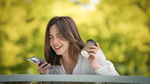 コーヒーを飲み、紙コップを使用して公園に行く若いスタイリッシュな女性若い人たちの女性の手