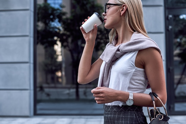 Young stylish woman drinks coffe close up view