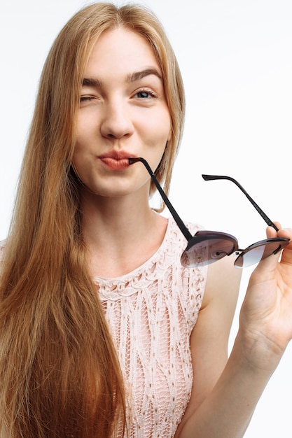 Young stylish woman posing with glasses on white wall