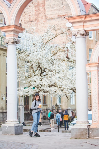 Young stylish woman walking by street with coffee cup