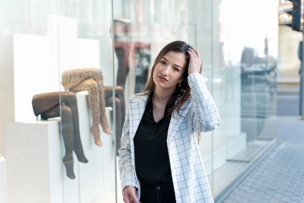 Young stylish woman walks through the mall. Portrait of girl on window case background.