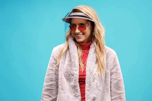 Young stylish woman wearing face shield against blue background