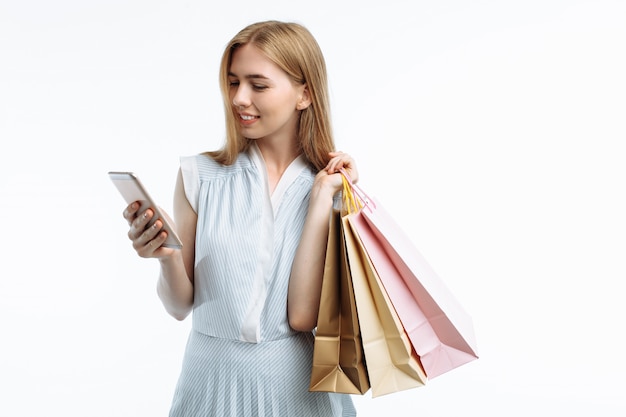 Giovane donna alla moda con i sacchetti della spesa e lo smartphone