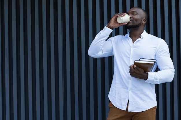 Young successful AfricanAmerican man with notebook and coffee