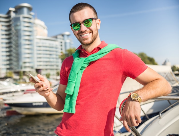 Young successful businessman holding time on the yacht.