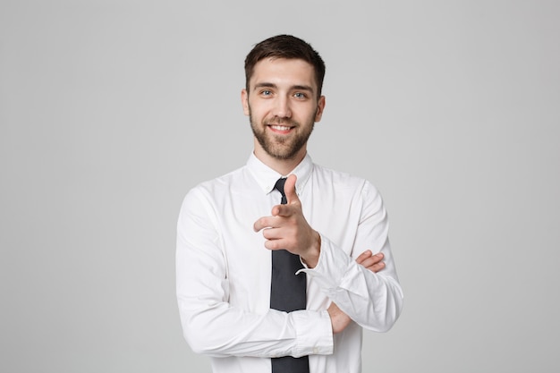 Young successful businessman pointing direction with finger over dark grey background. Copy space.