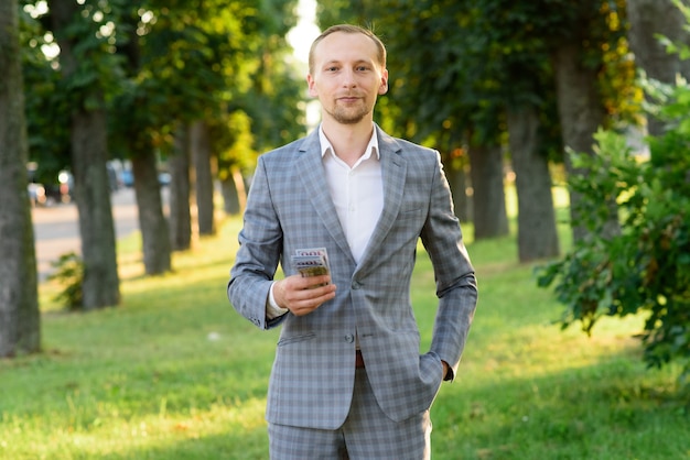 Young successful businessman shows money in his hand.