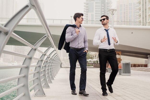 Young successful businessman in suit walking in Dubai Marine and talking about new business steps .