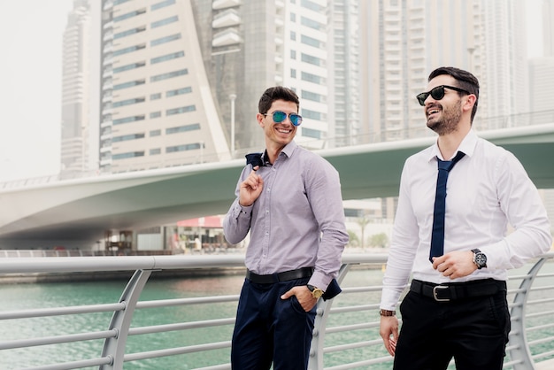 Young successful businessman in suit walking in Dubai Marine and talking about new business steps .
