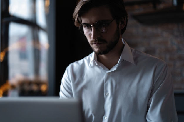 Young successful businessman working on a laptop while sitting in cafe.