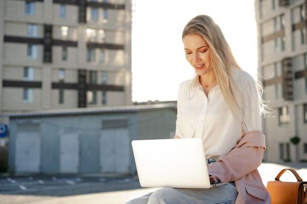 Young successful businesswoman using laptop for work outdoors