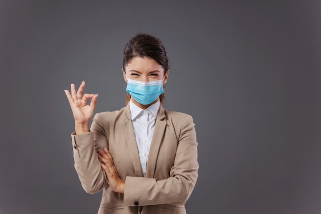 Young successful businesswoman with protective face mask standing