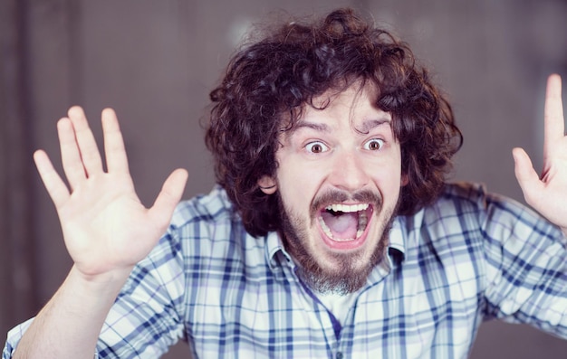 young successful casual businessman screaming in front of a concrete wall at new startup office