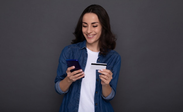 オンラインショッピング中に手にクレジットカードを持つ若い成功した幸せな女性