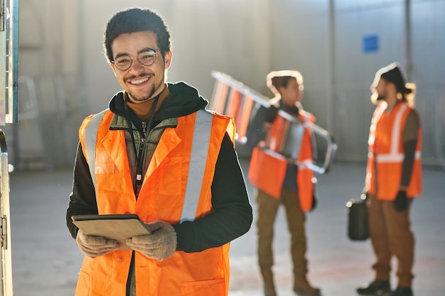 Photo young successful male technician looking at camera while using tablet