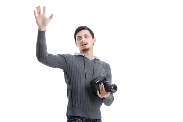 Young successful professional photographer in shirt with DSLR digital camera waving Hello isolated on white background