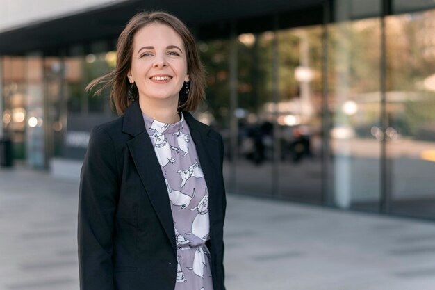 Young successful woman in black jacket on office center background Smiling business woman