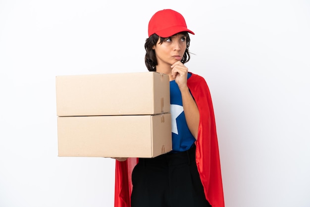 Young superhero delivery girl isolated on pink background having doubts and thinking