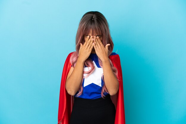 Young superhero woman with pink hair isolated on blue background with tired and sick expression