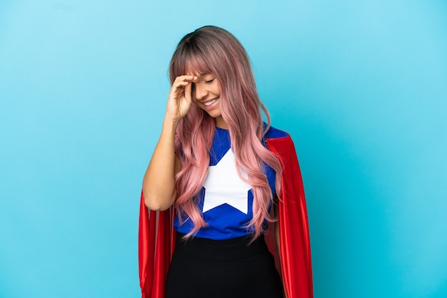 Фото Молодая женщина супергероя с розовыми волосами изолирована на синем фоне смеясь