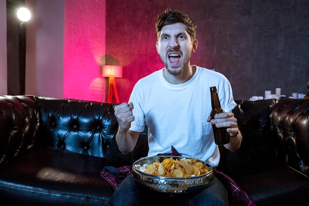 Young supporter man watching football game on television sitting