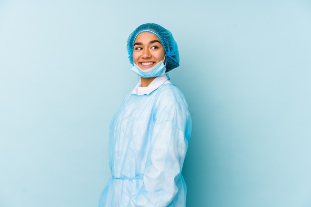 Молодой хирург Азиатская женщина смотрит в сторону, улыбаясь, веселый и приятный.