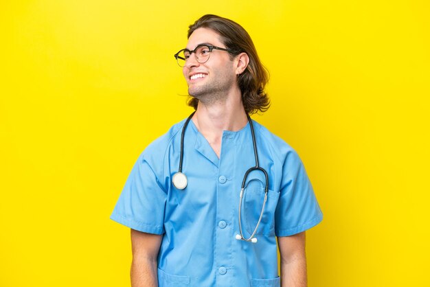 Young surgeon caucasian man isolated on yellow background looking side