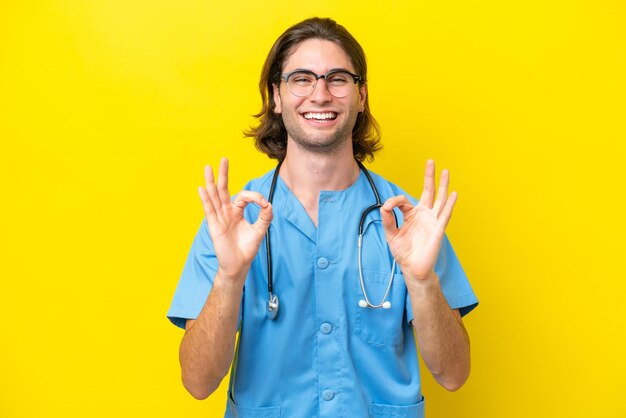 Young surgeon caucasian man isolated on yellow background showing an ok sign with fingers