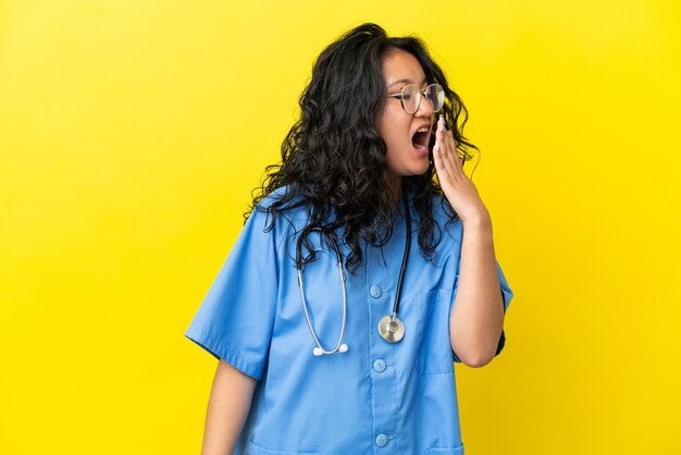 Young surgeon doctor asian woman isolated on yellow background yawning and covering wide open mouth with hand